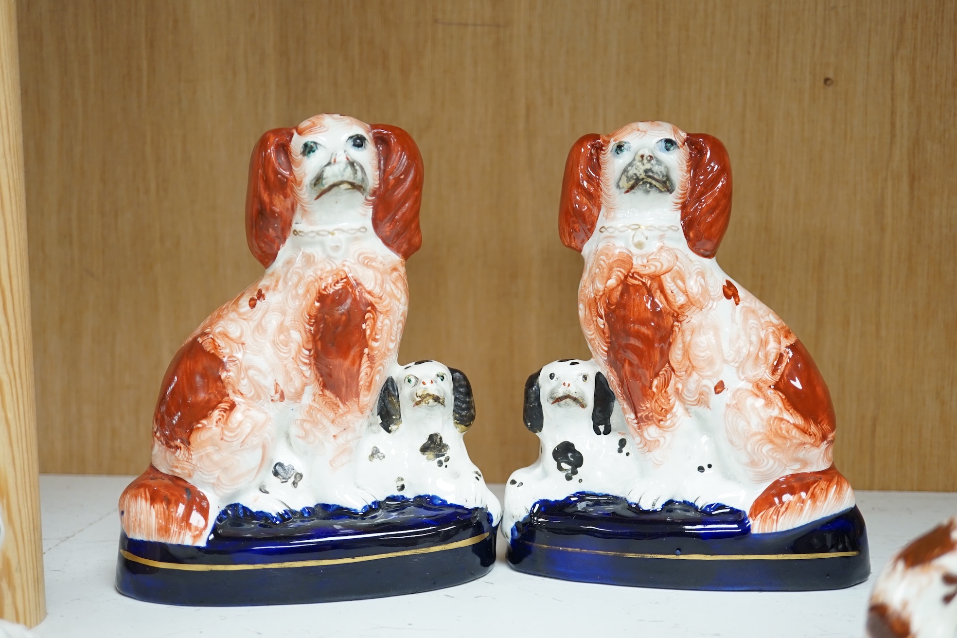 A pair of mid 19th century Staffordshire spaniel and puppy groups, a pair of smaller Staffordshire spaniel figures, and a pair of Staffordshire porcelain figures of standing terriers, c.1835, together with a Continental